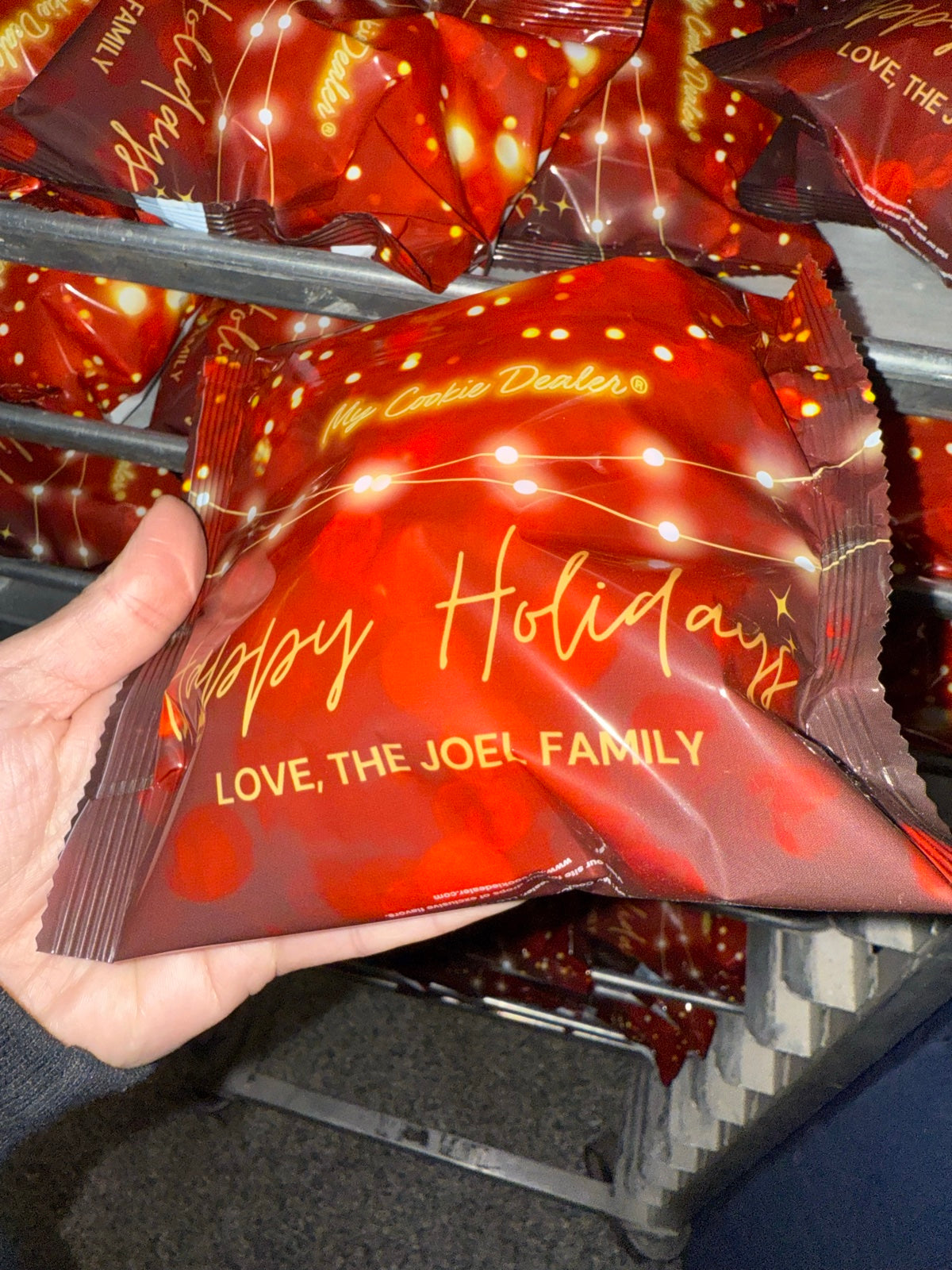 Hand holding a custom-printed Happy Holidays cookie wrapper with a personalized family message